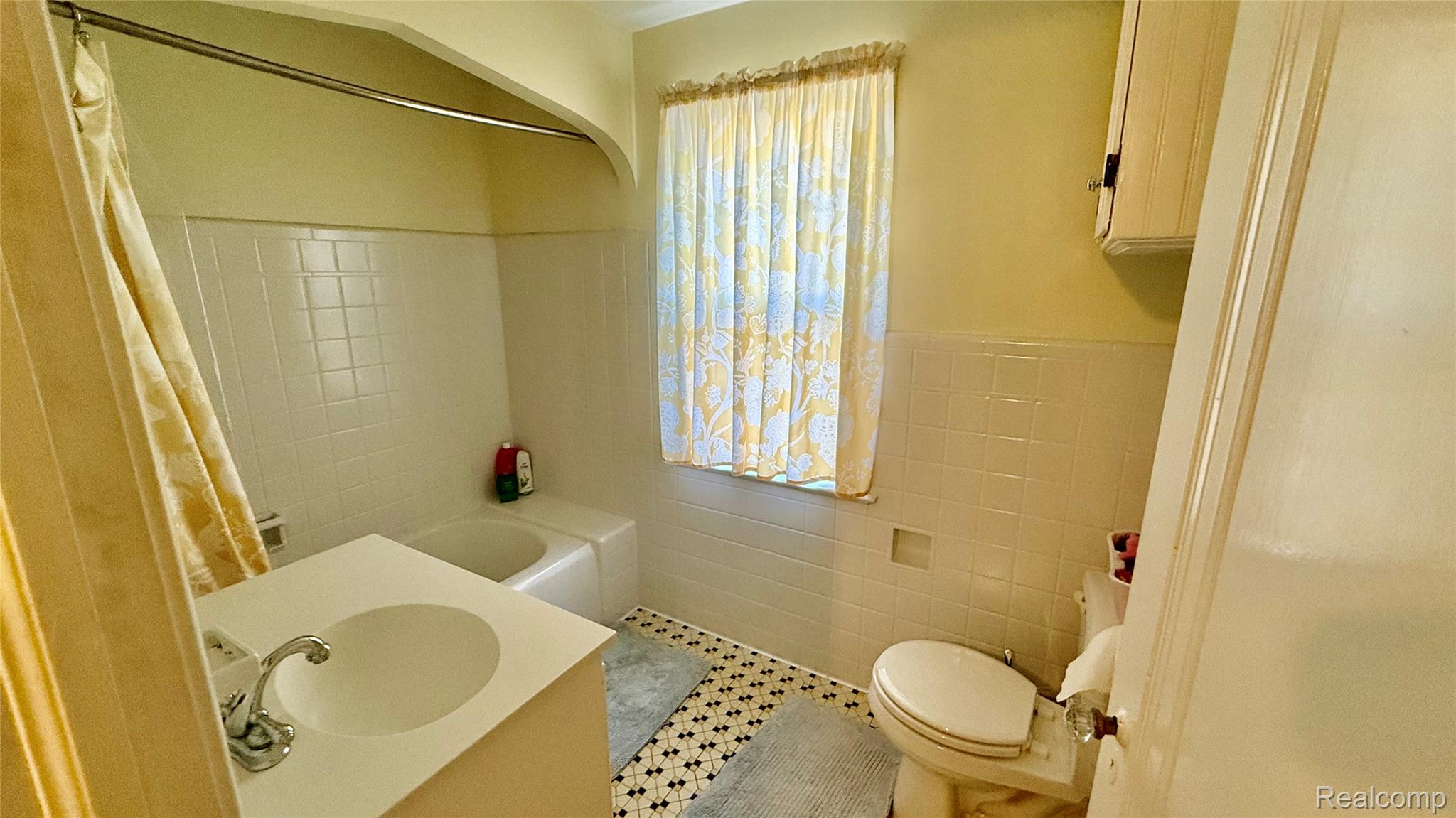 889 Rivard Boulevard Grosse Pointe, MI 48230 - Photo 12 of 18 Bathroom featuring white tile walls, a built-in tub, white vanity with integrated sink, and patterned floor tile