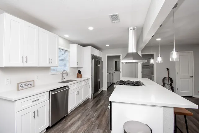 a kitchen with stainless steel appliances granite countertop a white stove top oven and white cabinets