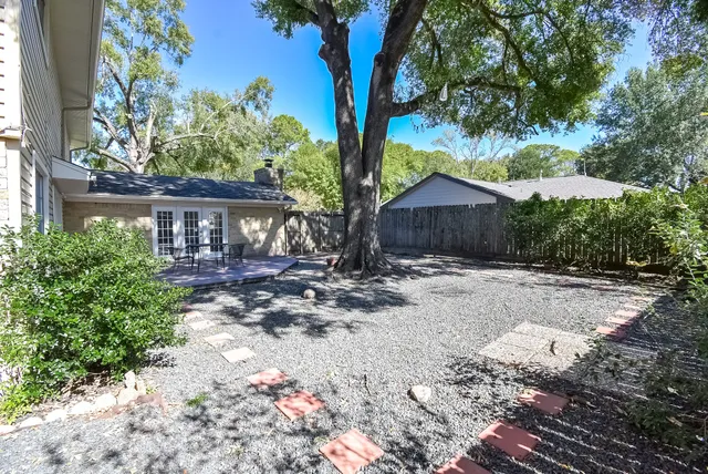 a view of a backyard with large trees and wooden fence