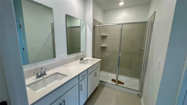 a bathroom with a double vanity sink mirror and shower