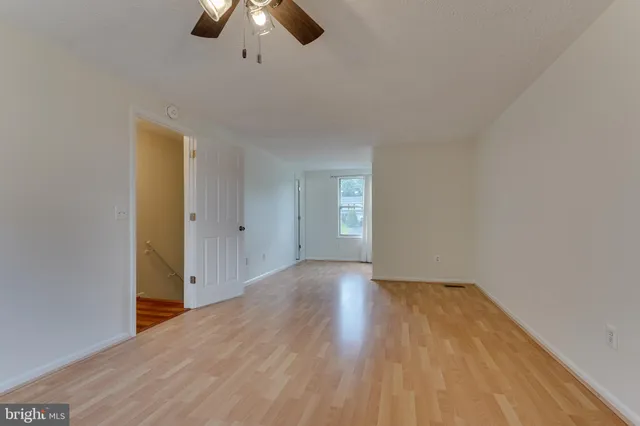 a view of an empty room with wooden floor and window