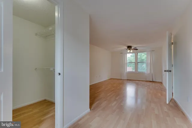 a view of an empty room with window and wooden floor