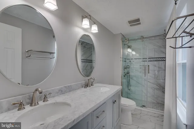 a bathroom with a granite countertop sink toilet a mirror and shower