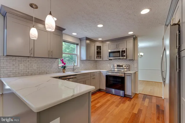 a kitchen with stainless steel appliances granite countertop a sink dishwasher a stove and a refrigerator