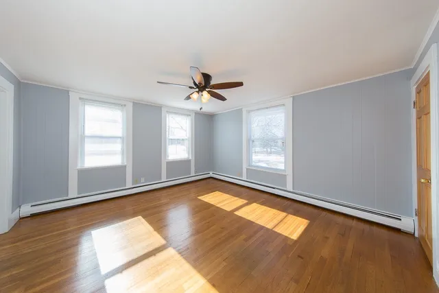 a view of empty room with wooden floor and fan