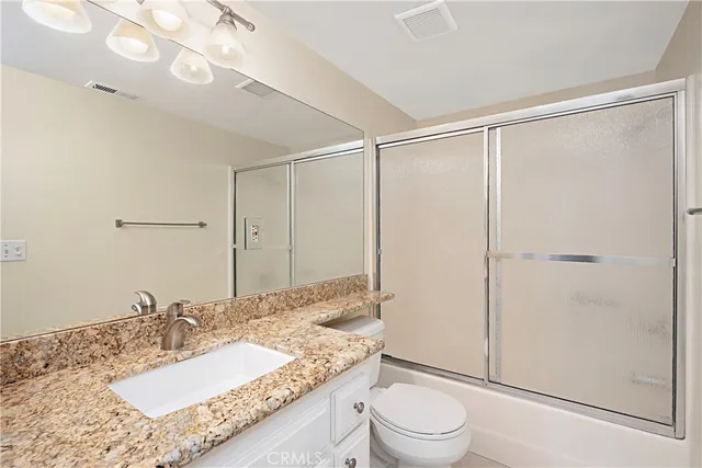 a bathroom with a granite countertop sink mirror vanity and toilet