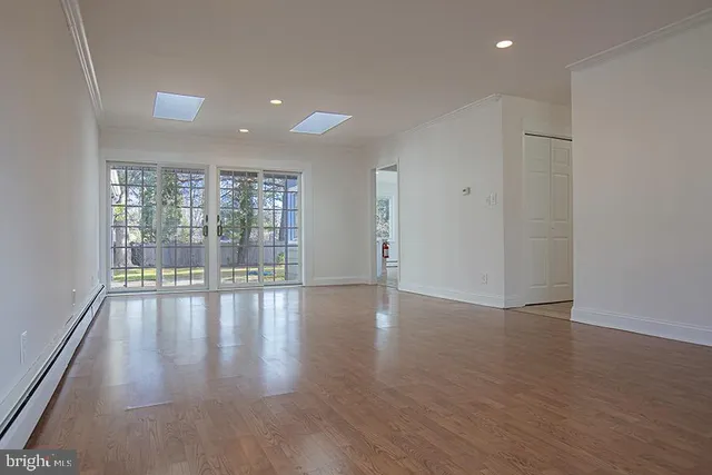 a view of empty room with wooden floor and floor to ceiling window