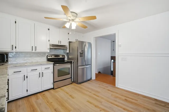 a kitchen with a refrigerator a stove cabinets and wooden floor