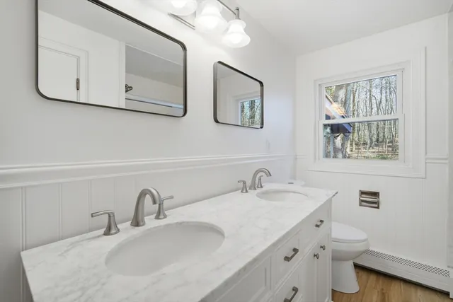 a bathroom with double vanity sink a toilet and a mirror