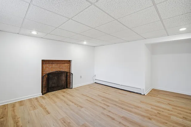 a view of empty room with wooden floor and fireplace