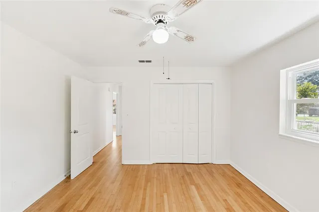 an empty room with a window and a ceiling fan