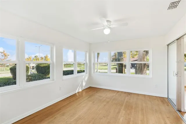 a view of an empty room with a window and wooden floor