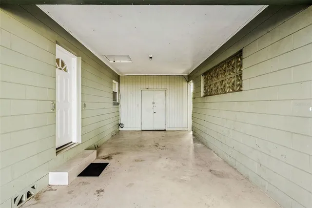 a backyard of a house with plants and large tree