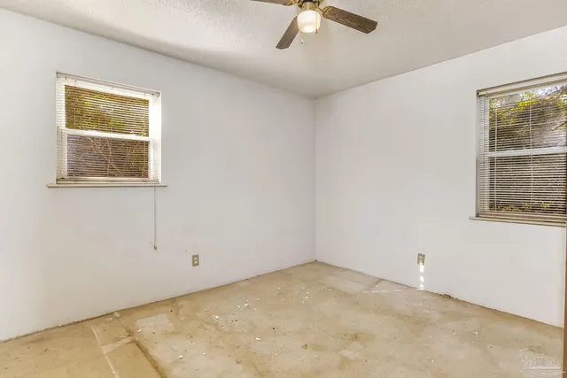 an empty room with a ceiling fan and a window