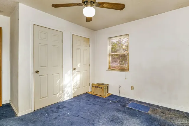 an empty room with a ceiling fan & entryway