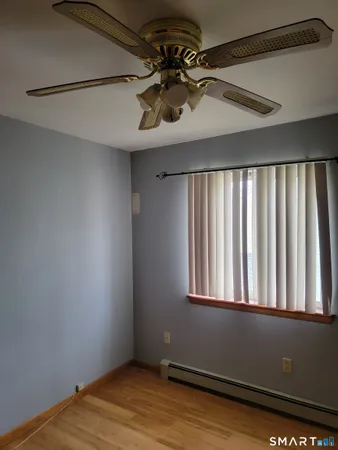 an empty room with wooden floor closet and windows