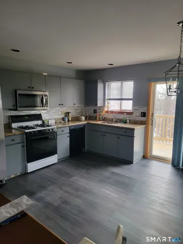 a kitchen with stainless steel appliances granite countertop wooden cabinets a sink a stove a refrigerator with grey walls and wooden floor