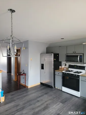 a kitchen with stainless steel appliances a stove a refrigerator and a view of living room