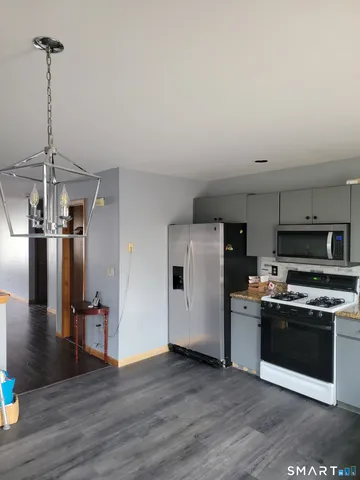 a kitchen with stainless steel appliances a stove a refrigerator and a view of living room