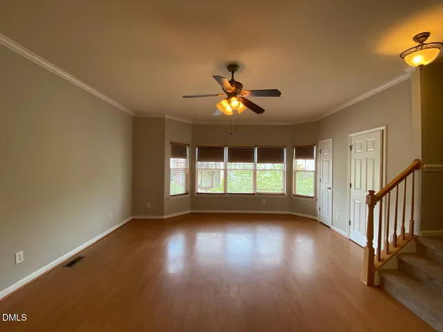 a view of empty room with wooden floor and fan