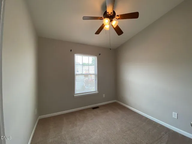 an empty room with a chandelier fan and windows
