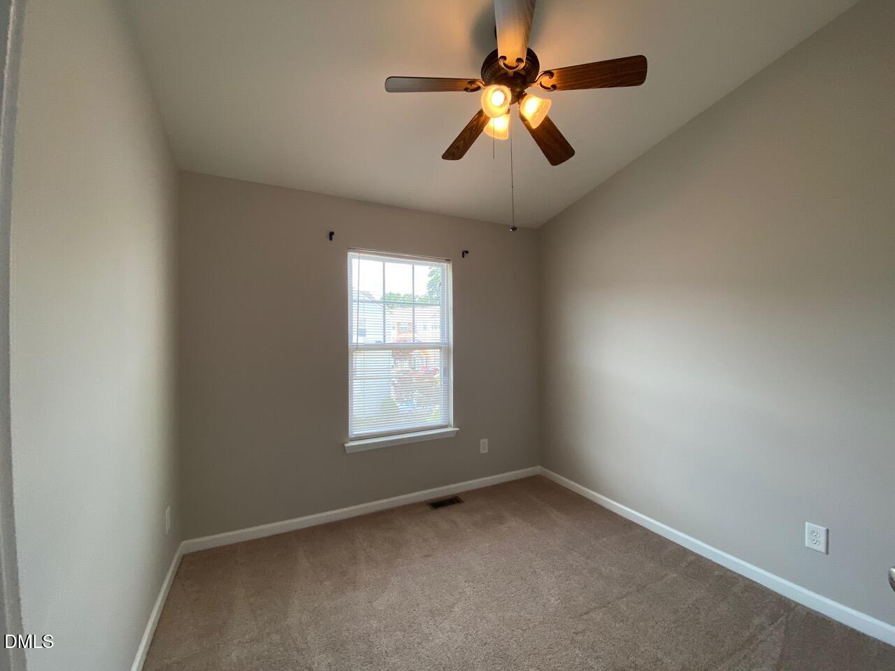134 Darley Dale Loop Apex, NC 27502 - Photo 20 of 23 an empty room with a chandelier fan and windows