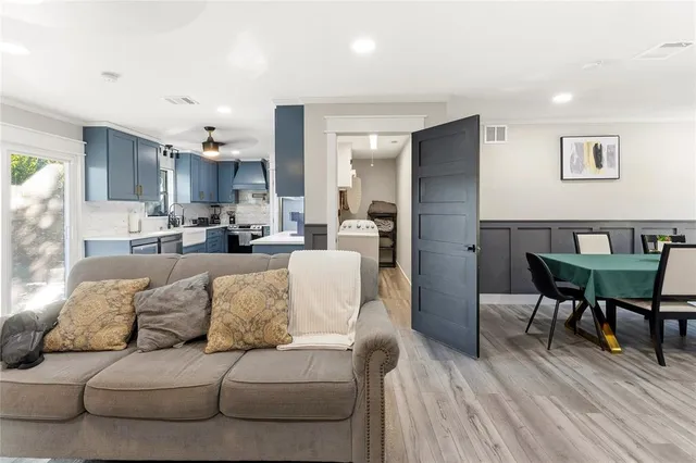 a living room with furniture and a dining table with wooden floor