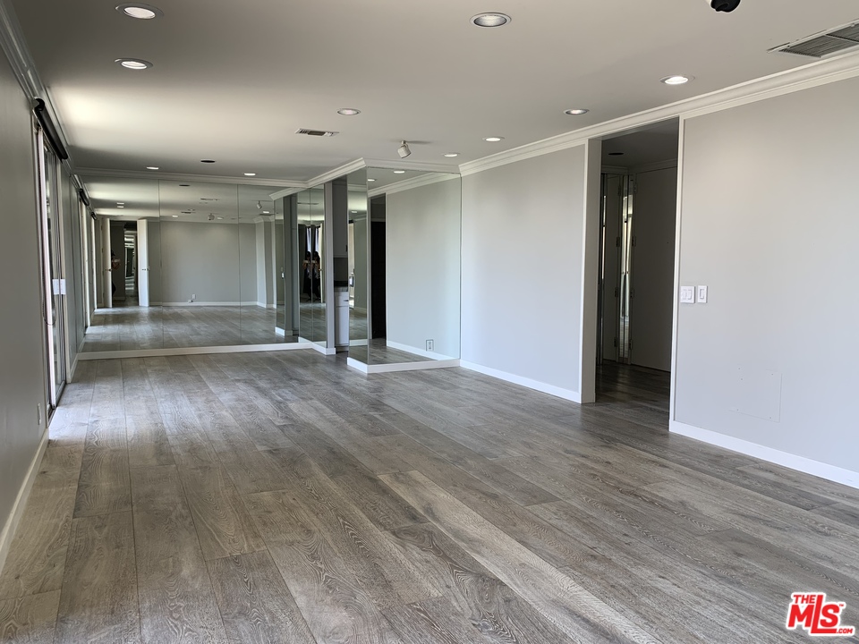 an empty room with wooden floor and natural light