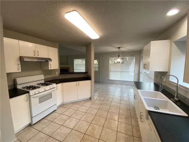 a large white kitchen with a stove a sink dishwasher and a refrigerator with wooden floor