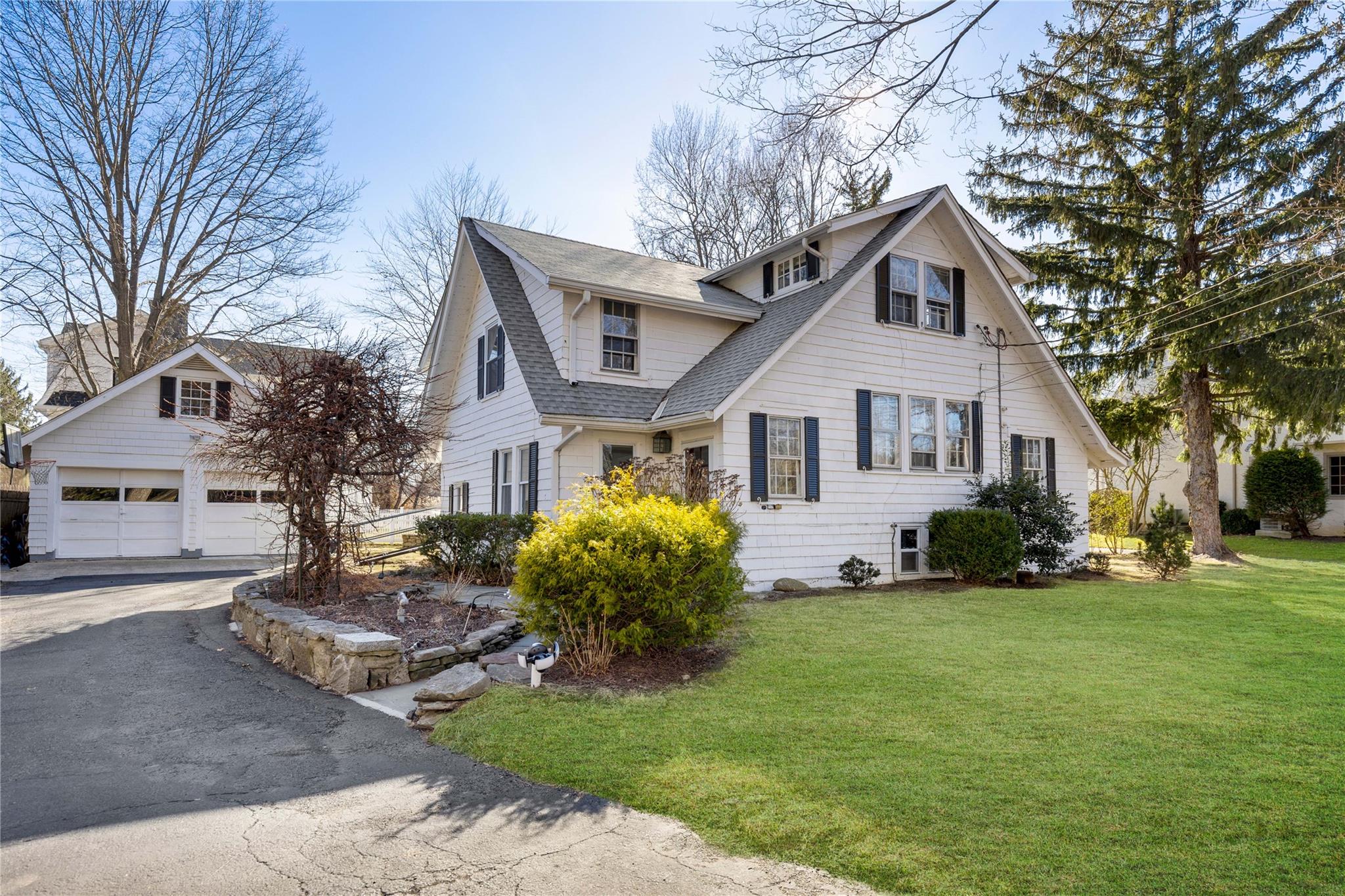 View of front of house featuring a wide front lawn and detached garage.