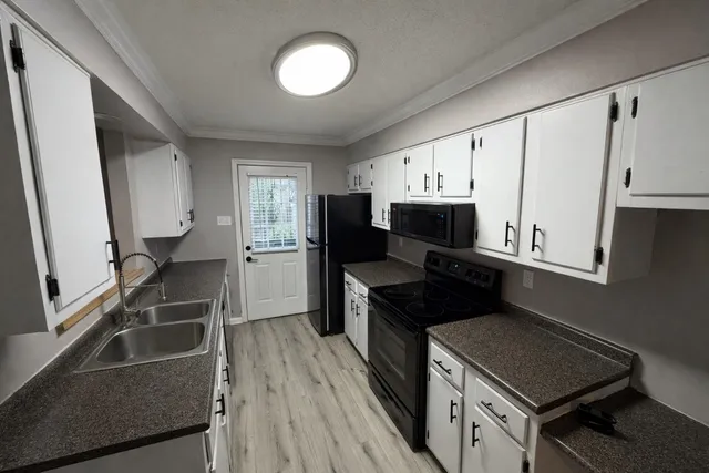 a kitchen with granite countertop a refrigerator stove and sink
