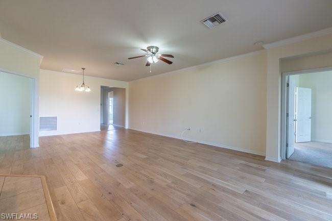 8887 Ravello Court Naples, FL 34114 - Photo 11 of 22 Empty room featuring ceiling fan with notable chandelier, light hardwood / wood-style floors, and ornamental molding
