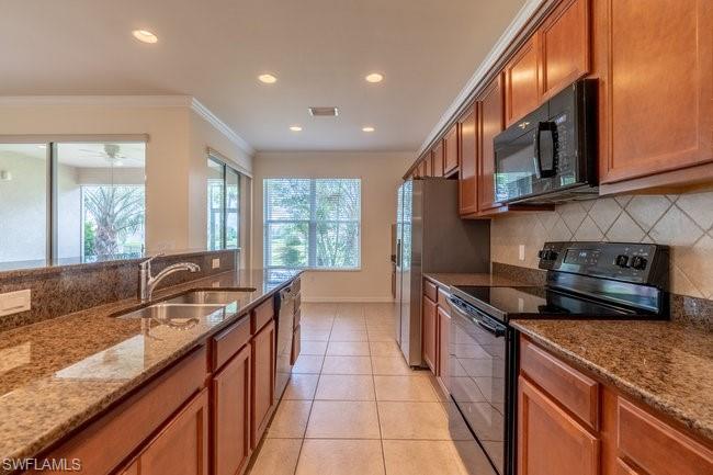 8887 Ravello Court Naples, FL 34114 - Photo 13 of 22 Kitchen with light stone counters, light tile patterned flooring, sink, black appliances, and crown molding