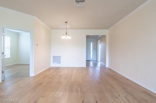 Unfurnished room featuring light wood-type flooring, crown molding, and a chandelier