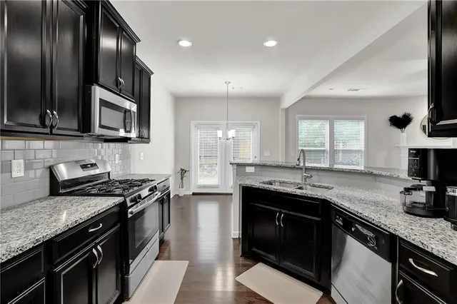 a open kitchen with stainless steel appliances kitchen island granite countertop a refrigerator a stove a microwave oven a sink with island and chairs