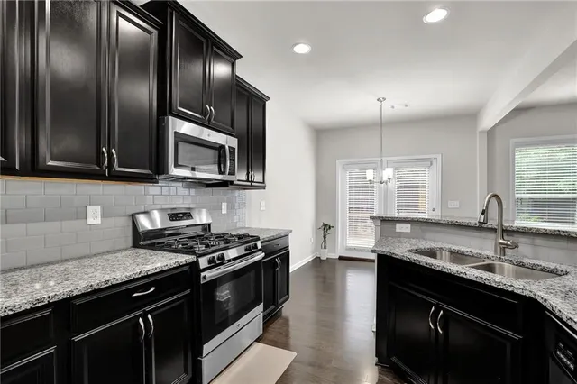 a kitchen with granite countertop a sink stove and refrigerator