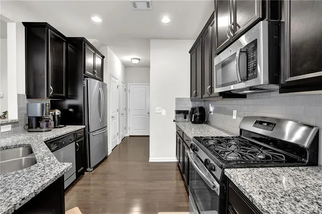 a kitchen with stainless steel appliances kitchen island granite countertop a stove a sink and a microwave