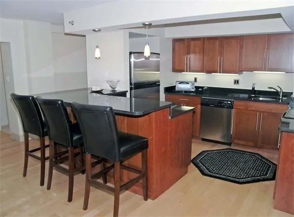 a kitchen with granite countertop a sink cabinets and stainless steel appliances