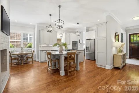 a kitchen with stainless steel appliances kitchen island granite countertop a table chairs and white cabinets