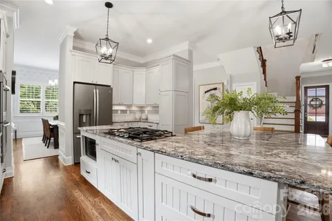 a kitchen with a stove a sink a center island and wooden floor