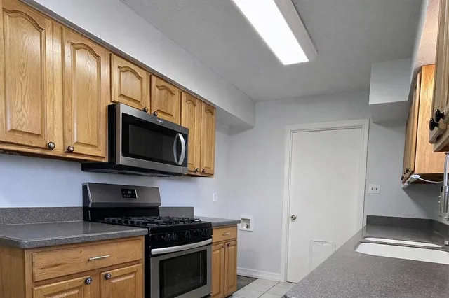 a kitchen with stainless steel appliances granite countertop white cabinets a stove top oven a sink and dishwasher