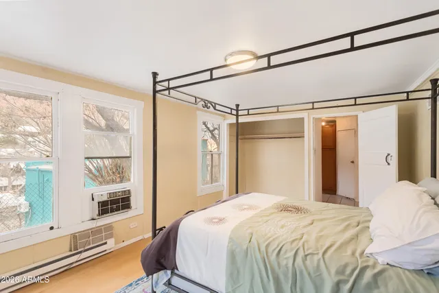 a bedroom with a bed large mirror with a wooden floor
