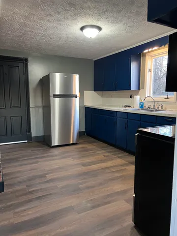 a kitchen with stainless steel appliances granite countertop a refrigerator a sink dishwasher and wooden cabinets with wooden floor