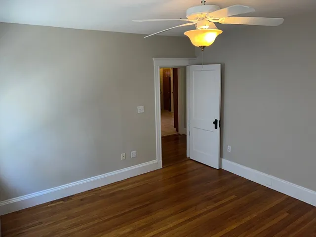 a view of an empty room with wooden floor and window