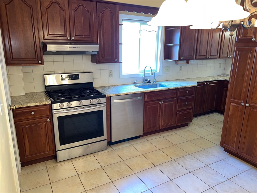 84 Melrose Street, Unit 1 Arlington, MA 02474 - Photo 29 of 42 a kitchen with stainless steel appliances granite countertop a stove a sink and a microwave