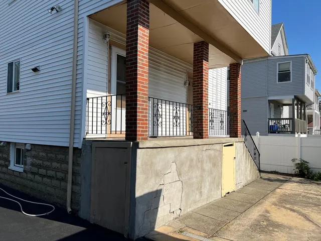 a view of a house with a barbeque and wooden stairs