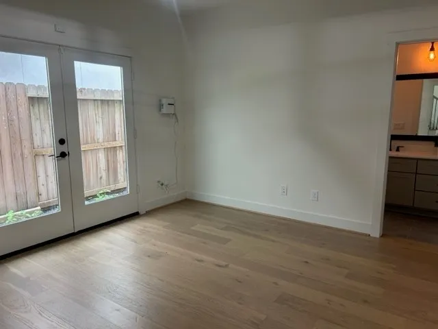 a view of an empty room with a window and wooden floor