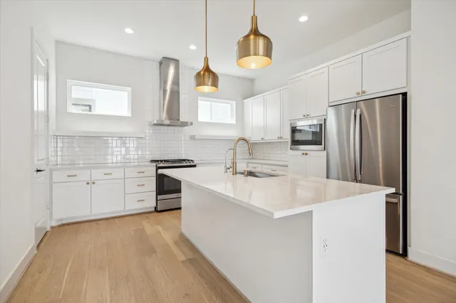 a large kitchen with stainless steel appliances a sink a stove a refrigerator and cabinets