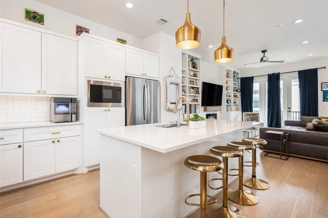 a kitchen with stainless steel appliances kitchen island granite countertop a table chairs and a refrigerator