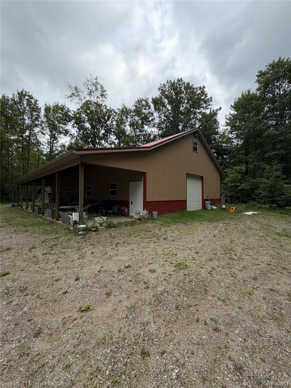 1873 Pierce Road Caro, MI 48723 - Photo 5 of 27 Spacious outbuilding featuring a tan and red exterior, a covered porch spanning the length of the building, a red metal roof, and a prominent garage door